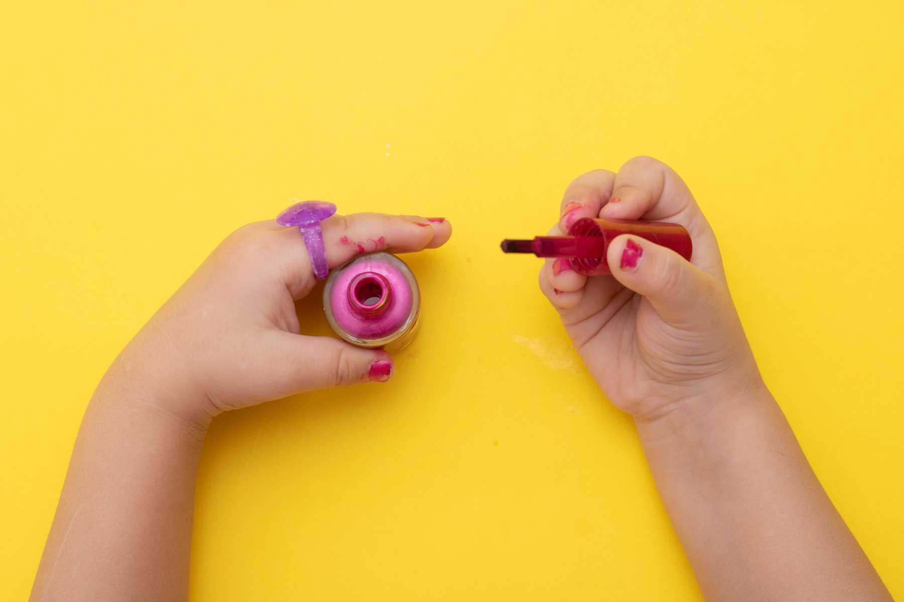 Girl applying pink nail polish, kids cosmetics